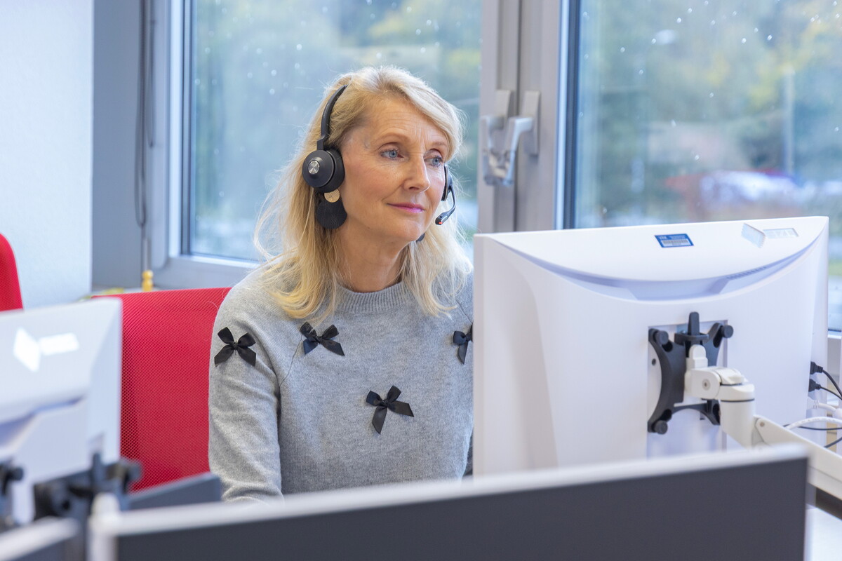 Medewerkster aan de telefoon en achter de computer