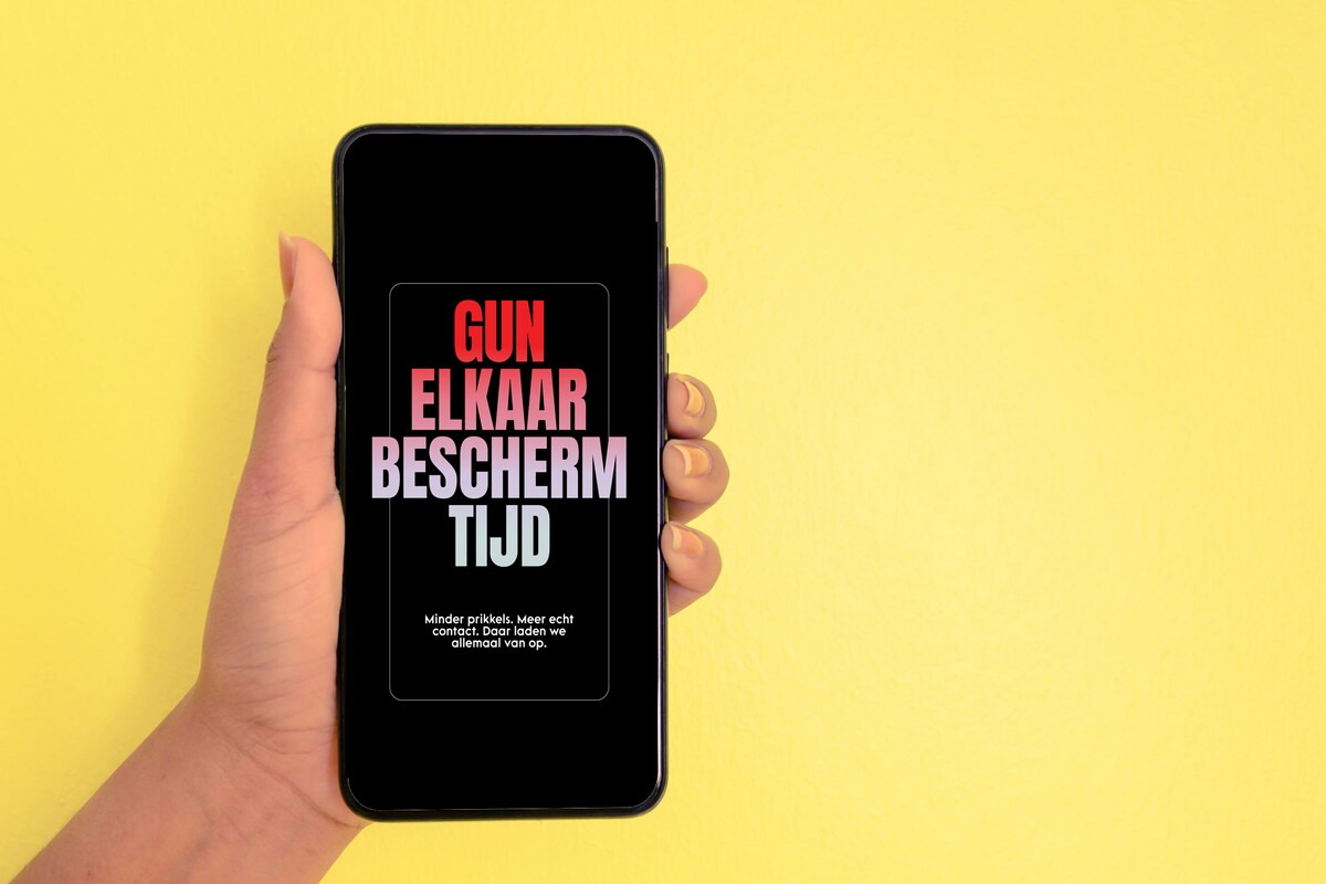 Iemand houdt een mobiele telefoon vast met daarop de tekst Gun elkaar beschermtijd