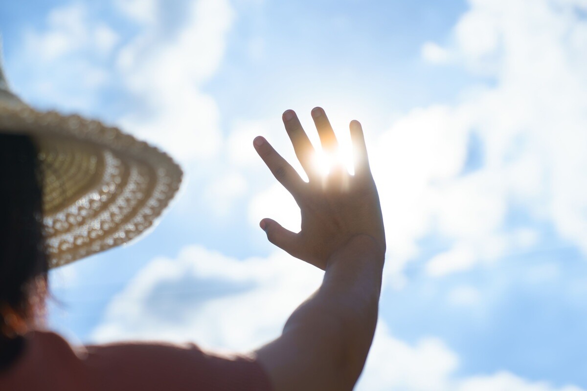 Persoon met zonnehoed en felle zon