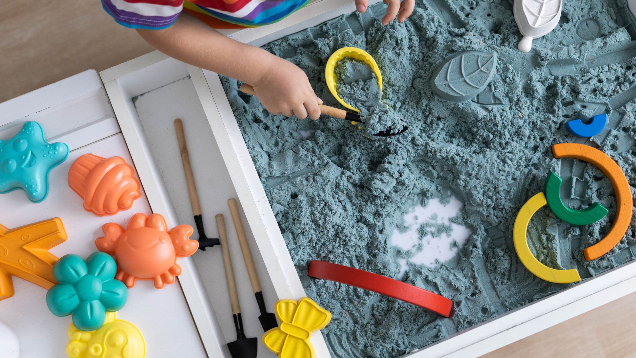 Kind speelt aan een tafel met speelzand