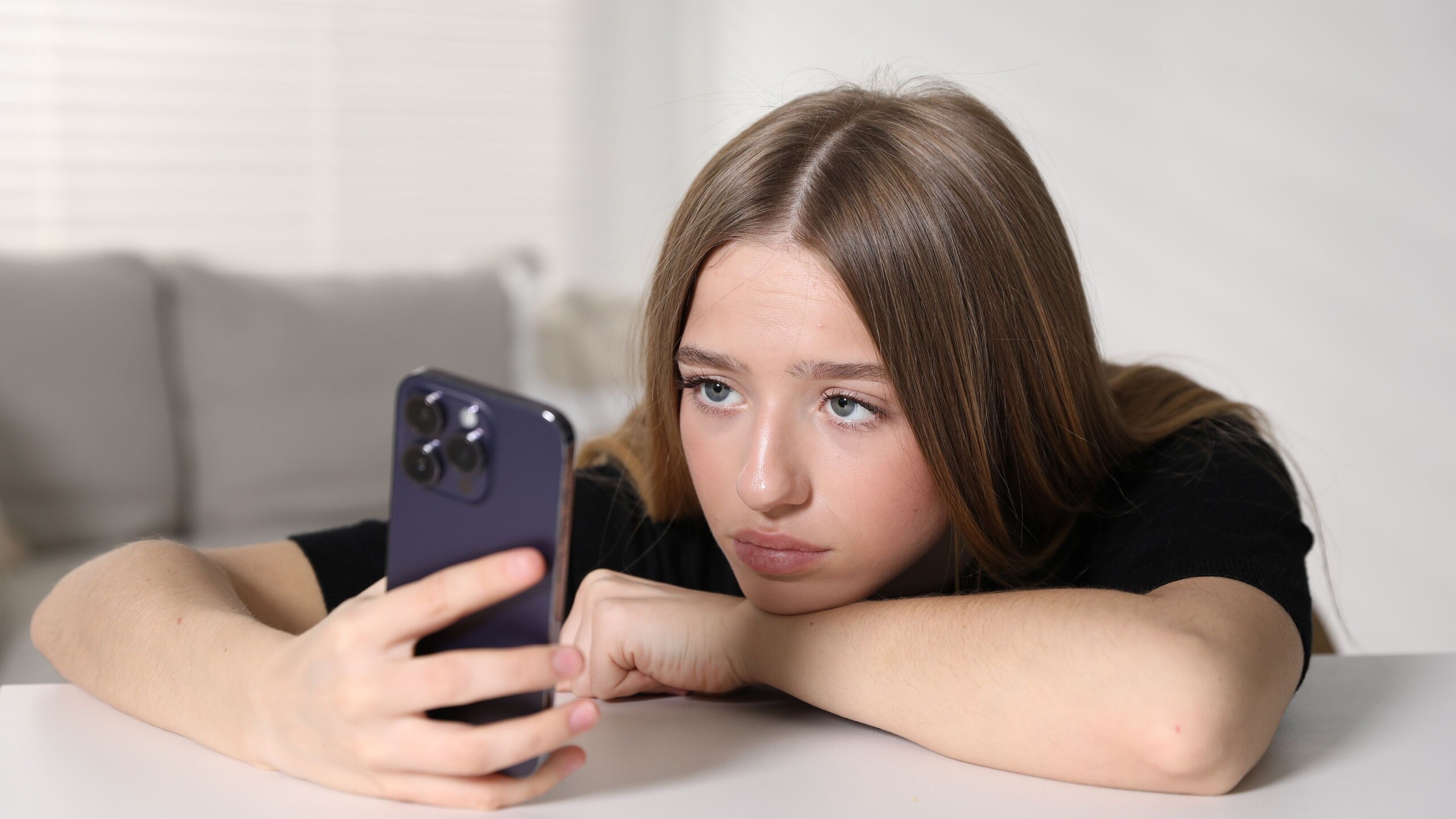 Tiener meisje kijkt verveeld op haar mobiele telefoon