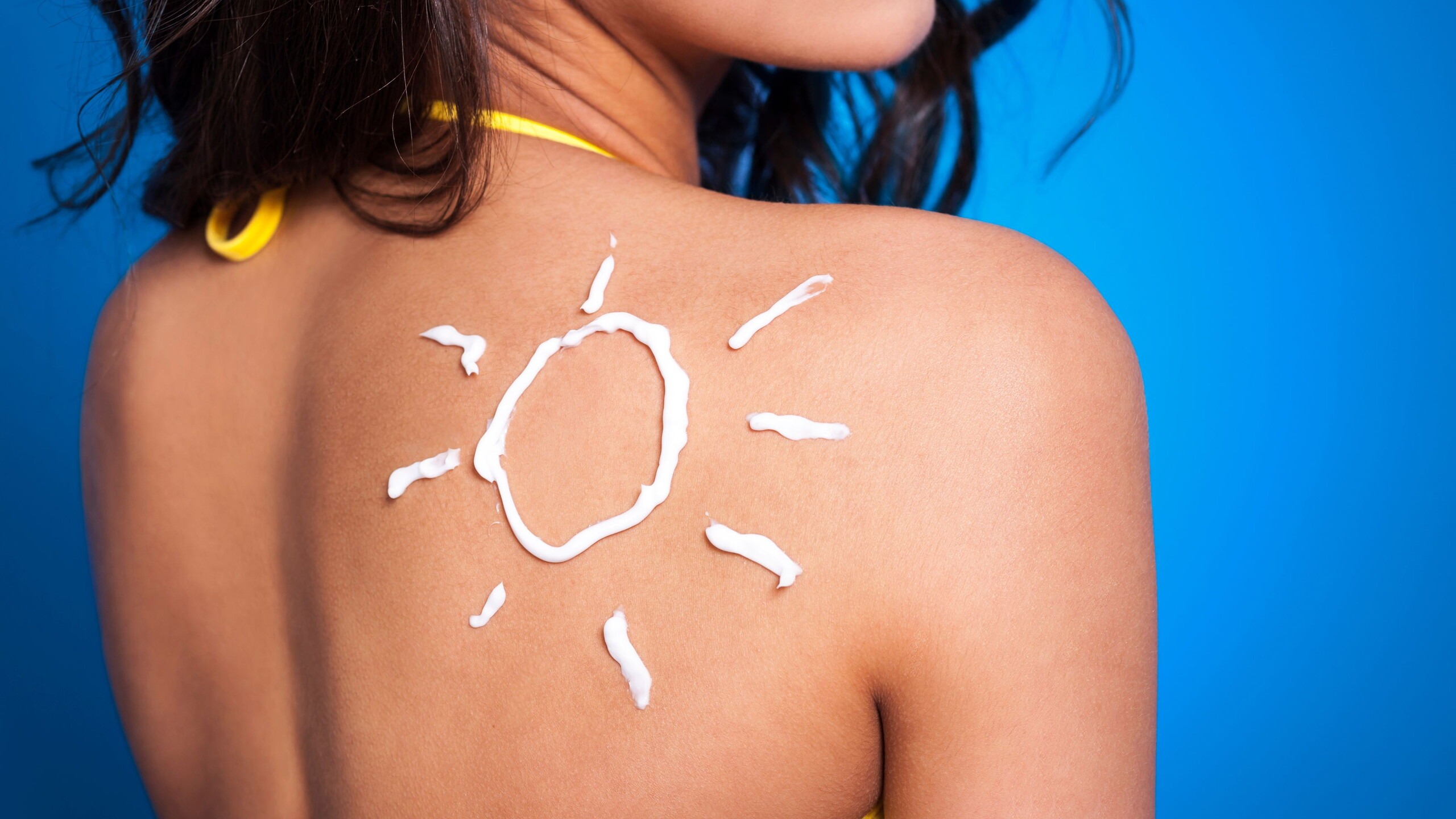 Vrouw met zon op rug van zonnebrandcreme