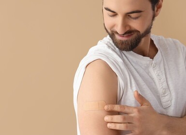 Man laat zijn pleister op zijn arm zien na een vaccinatie